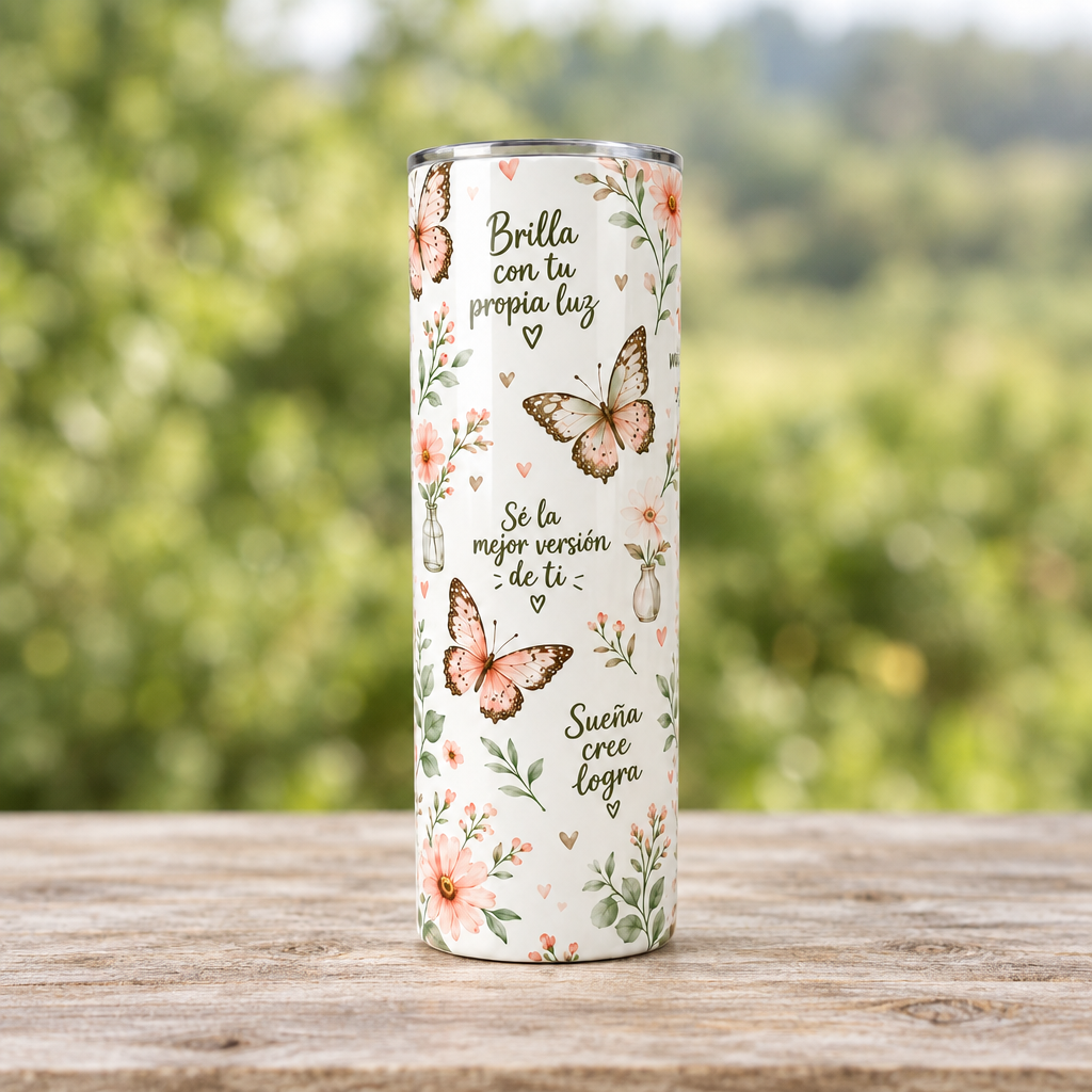 Vaso tumbler de mariposas completo sobre una mesa de madera y fondo verde desenfocado