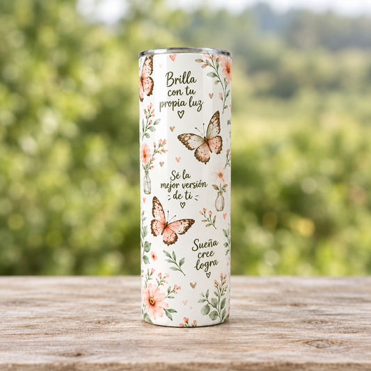 Vaso tumbler de mariposas completo sobre una mesa de madera y fondo verde desenfocado
