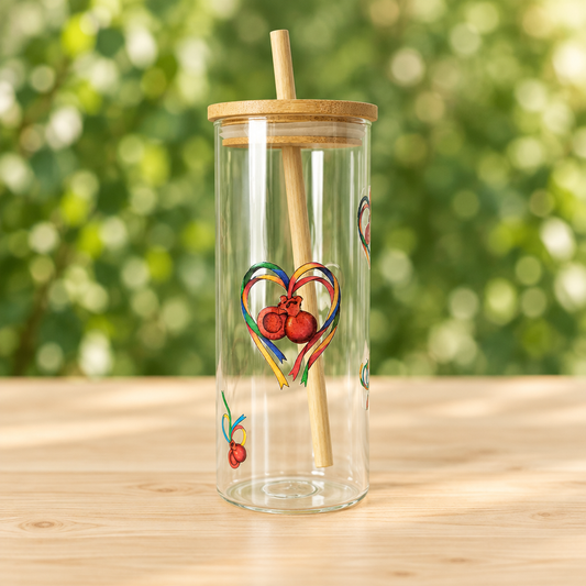 Vaso de cristal con pajita y dibujo de castañuelas maragatas sobre mesa de madera y fondo verde desenfocado