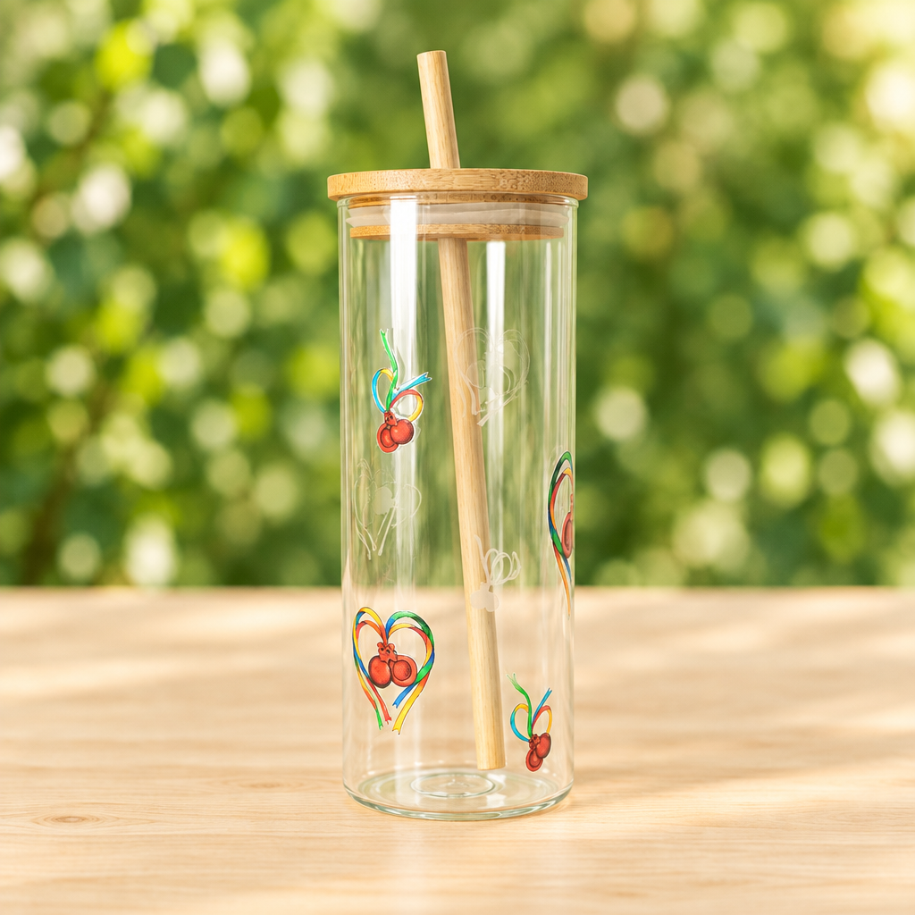 Vista lateral del vaso de cristal con pajita y motivos maragatos sobre madera y fondo verde